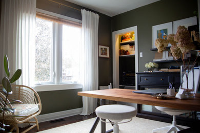 Photo of a small eclectic home office in Calgary with green walls, dark hardwood floors, a freestanding desk and brown floor.