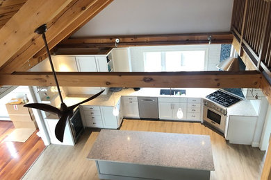 Example of a large transitional u-shaped light wood floor, beige floor and exposed beam kitchen pantry design in Boston with an undermount sink, recessed-panel cabinets, white cabinets, quartzite countertops, blue backsplash, glass tile backsplash, stainless steel appliances, an island and multicolored countertops