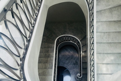 Expansive modern curved metal railing staircase in Melbourne with marble treads, marble risers and wainscoting.