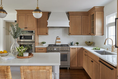 Example of a mid-sized classic medium tone wood floor kitchen design in New York with recessed-panel cabinets, light wood cabinets, quartz countertops, white backsplash, quartz backsplash, an island and white countertops