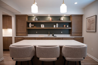 Mid-sized traditional galley eat-in kitchen in Detroit with an undermount sink, flat-panel cabinets, light wood cabinets, quartzite benchtops, vinyl floors, with island, brown floor and white benchtop.