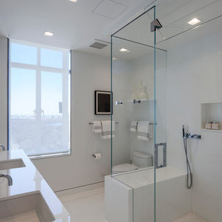 Exemple d'une grande salle de bain principale tendance avec un placard à porte plane, des portes de placard blanches, une douche ouverte, un carrelage blanc, des plaques de verre, un lavabo encastré, un plan de toilette en verre, un WC à poser et un mur blanc.