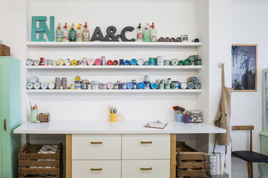 Example of a mid-sized eclectic built-in desk concrete floor craft room design in Other with white walls