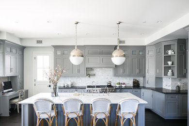 This is an example of a transitional u-shaped kitchen in Los Angeles with a farmhouse sink, shaker cabinets, grey cabinets, grey splashback, subway tile splashback, dark hardwood floors, with island, black floor and black benchtop.