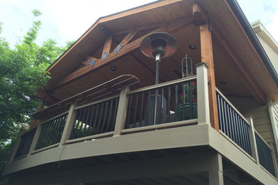 Large backyard second story mixed material railing deck photo in Denver with a roof extension