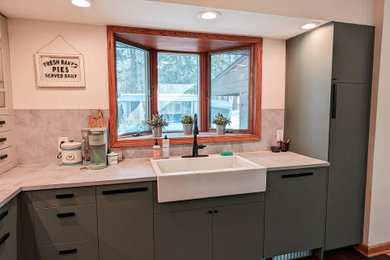 Example of a mid-sized cottage u-shaped dark wood floor, brown floor and exposed beam kitchen pantry design in Miami with a farmhouse sink, flat-panel cabinets, green cabinets, quartz countertops, gray backsplash, cement tile backsplash, stainless steel appliances, a peninsula and white countertops