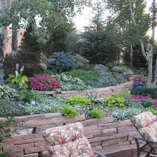Photo of a large contemporary backyard partial sun garden in Denver with a retaining wall and natural stone pavers.