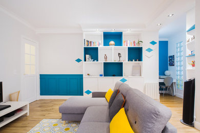 Exemple d'un grand salon tendance ouvert avec une bibliothèque ou un coin lecture, un mur beige, un sol en bois brun, aucune cheminée, un téléviseur dissimulé et un sol multicolore.