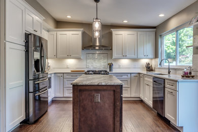 Mid-sized transitional u-shaped brown floor eat-in kitchen photo in St Louis with white cabinets, white backsplash, subway tile backsplash, stainless steel appliances, an island, granite countertops and multicolored countertops