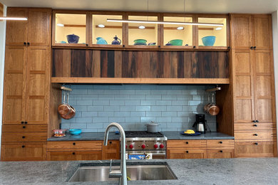 Large beach style medium tone wood floor and multicolored floor eat-in kitchen photo in Other with a single-bowl sink, shaker cabinets, medium tone wood cabinets, soapstone countertops, blue backsplash, porcelain backsplash, stainless steel appliances, an island and blue countertops