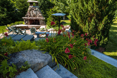 This is an example of a large transitional side yard shaded garden for summer in Portland Maine with a fire feature and natural stone pavers.