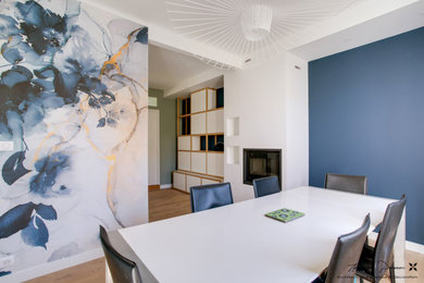 Cette image montre une salle à manger minimaliste de taille moyenne avec un mur bleu, parquet clair, une cheminée standard, un sol beige et du papier peint.