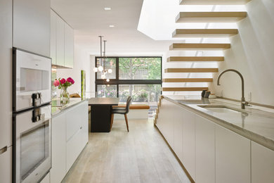 Example of a small minimalist galley beige floor eat-in kitchen design in New York with an undermount sink, flat-panel cabinets, white cabinets, quartzite countertops, beige backsplash, stone slab backsplash, stainless steel appliances, no island and beige countertops