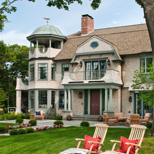 Klassisk inredning av ett beige trähus, med tre eller fler plan och mansardtak