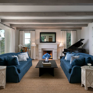 Mittelgroßes, Fernseherloses Mediterranes Musikzimmer mit weißer Wandfarbe, braunem Holzboden, Kamin und verputztem Kaminsims in Santa Barbara