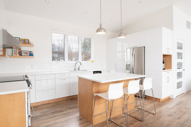 Inspiration for a contemporary kitchen in Other with an undermount sink, flat-panel cabinets, white cabinets, white splashback, subway tile splashback, stainless steel appliances, medium hardwood floors, with island and white benchtop.