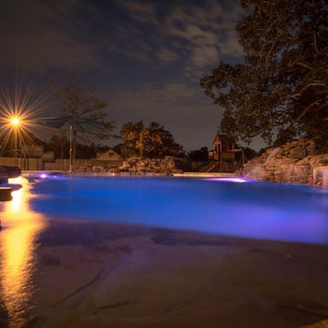 Rustic lagoon style pool with a fire pit, water falls and a hot tub