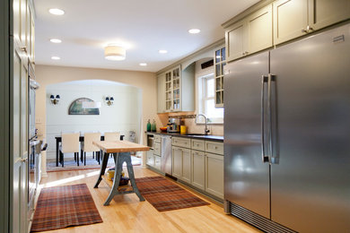 Enclosed kitchen - large transitional galley light wood floor and beige floor enclosed kitchen idea in Chicago with an undermount sink, shaker cabinets, green cabinets, solid surface countertops, beige backsplash, subway tile backsplash, stainless steel appliances and an island