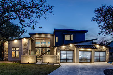 This is an example of a large transitional two-storey beige house exterior in Austin with a metal roof and stone veneer.