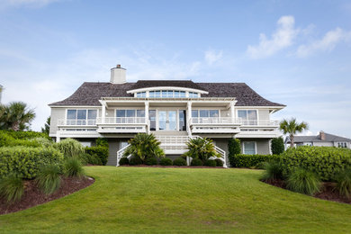 Large beach style two-storey beige house exterior in Other with wood siding, a hip roof and a shingle roof.