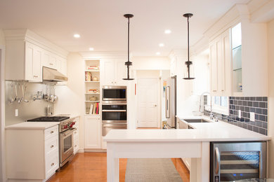 Eat-in kitchen - mid-sized transitional medium tone wood floor eat-in kitchen idea in Other with a farmhouse sink, shaker cabinets, white cabinets, quartz countertops, blue backsplash, subway tile backsplash, stainless steel appliances, a peninsula and white countertops