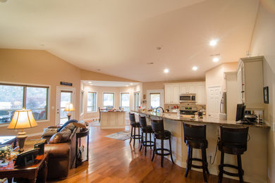 Huge transitional l-shaped medium tone wood floor kitchen photo in Other with an undermount sink, white cabinets, granite countertops, beige backsplash, ceramic backsplash, stainless steel appliances, two islands and recessed-panel cabinets