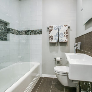 Ispirazione per una piccola stanza da bagno chic con vasca/doccia, WC monopezzo, piastrelle bianche, piastrelle di vetro, pareti grigie, pavimento in gres porcellanato e lavabo sospeso