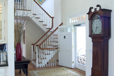 Foyer - mid-sized traditional medium tone wood floor foyer idea in New York with white walls and a white front door