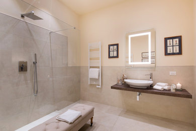 Esempio di una grande stanza da bagno moderna con WC a due pezzi, piastrelle beige, piastrelle in gres porcellanato, pareti beige, pavimento in gres porcellanato, lavabo a bacinella, top in legno, pavimento beige e mobile bagno sospeso