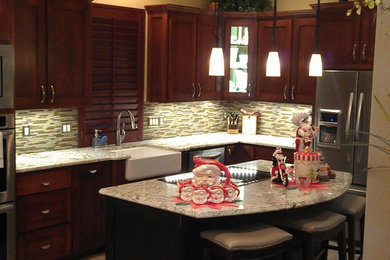 Transitional kitchen photo in Dallas with a farmhouse sink, flat-panel cabinets, dark wood cabinets, marble countertops, beige backsplash, stainless steel appliances and an island