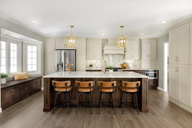 Inspiration for a large timeless u-shaped laminate floor and brown floor kitchen remodel in Minneapolis with an undermount sink, flat-panel cabinets, beige cabinets, quartz countertops, white backsplash, ceramic backsplash, stainless steel appliances, an island and white countertops