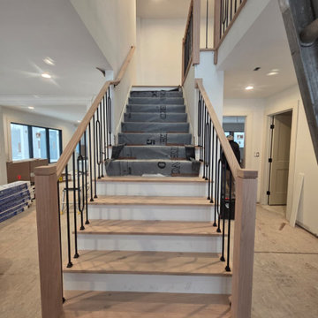 Stair Railing Installation Featuring Oval Metal Balusters and Red Oak Handrail