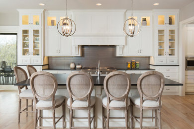Kitchen - coastal galley light wood floor and beige floor kitchen idea in Dallas with shaker cabinets, white cabinets, gray backsplash, stainless steel appliances, an island and black countertops