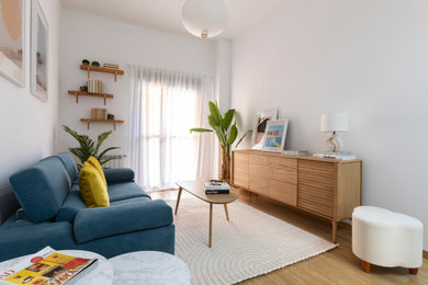Diseño de salón nórdico sin chimenea con paredes blancas, suelo de madera en tonos medios y suelo marrón