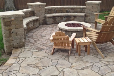Photo of a mid-sized traditional backyard full sun garden with a fire feature and natural stone pavers.