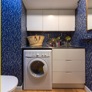 クライストチャーチの小さいモダンスタイルのおしゃれな家事室 (シングルシンク、インセット扉のキャビネット、白いキャビネット、御影石カウンター、青い壁、淡色無垢フローリング、茶色い床、黒いキッチンカウンター) の写真