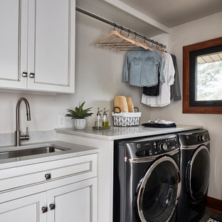 This is an example of a medium sized rustic single-wall utility room in Other with a submerged sink, recessed-panel cabinets, white cabinets, engineered stone countertops, white walls, porcelain flooring, a side by side washer and dryer, grey floors and white worktops.