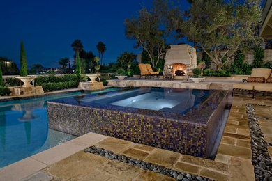 Inspiration for a large contemporary backyard stone and rectangular infinity hot tub remodel in Orange County