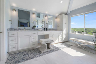 Example of a large transitional master white tile and porcelain tile porcelain tile, white floor, double-sink and vaulted ceiling alcove shower design in San Francisco with recessed-panel cabinets, white cabinets, a two-piece toilet, blue walls, an undermount sink, quartz countertops, a hinged shower door, white countertops, a niche and a built-in vanity