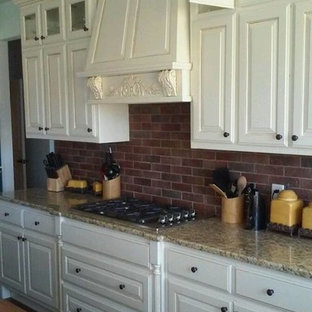 Idéer för stora linjära skafferier, med luckor med upphöjd panel, vita skåp, granitbänkskiva, rött stänkskydd, rostfria vitvaror och en köksö