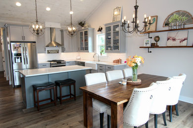Eat-in kitchen - mid-sized craftsman l-shaped vinyl floor and brown floor eat-in kitchen idea in Detroit with a farmhouse sink, shaker cabinets, gray cabinets, white backsplash, subway tile backsplash, stainless steel appliances, an island and white countertops