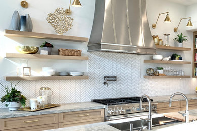 Example of a mid-sized beach style galley kitchen design in Orange County with a double-bowl sink, shaker cabinets, light wood cabinets, marble countertops, white backsplash, marble backsplash, stainless steel appliances and an island