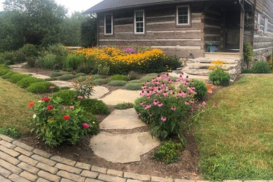 This is an example of a mid-sized traditional partial sun front yard stone landscaping in Charlotte for summer.