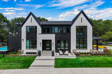 Large minimalist gray three-story brick and board and batten exterior home photo in Chicago with a shingle roof and a black roof