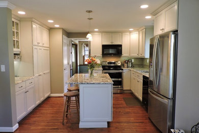 Photo of a mid-sized country galley eat-in kitchen in New York with an undermount sink, shaker cabinets, white cabinets, granite benchtops, green splashback, porcelain splashback, stainless steel appliances, dark hardwood floors and with island.