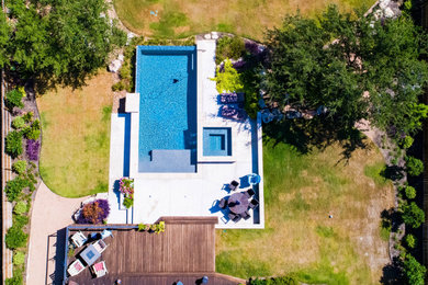 Large minimalist backyard concrete and rectangular infinity pool landscaping photo in Austin