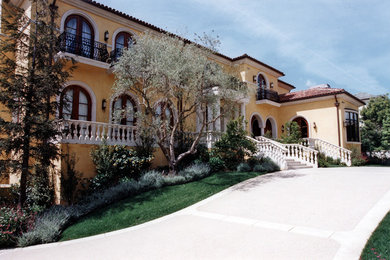 Expansive mediterranean three-storey stucco yellow exterior in Los Angeles with a hip roof.