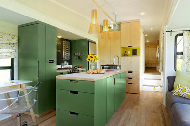 Example of a small l-shaped cork floor and beige floor open concept kitchen design in Burlington with a drop-in sink, flat-panel cabinets, green cabinets, laminate countertops, stainless steel appliances and an island