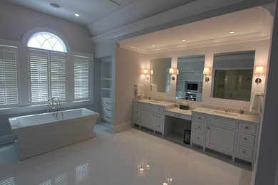 Inspiration for a large contemporary master bathroom in New York with an undermount sink, white cabinets, a freestanding tub and grey walls.