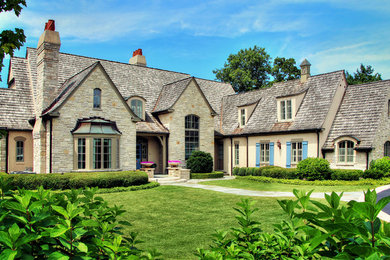 Elegant beige two-story stone exterior home photo in Chicago with a hip roof